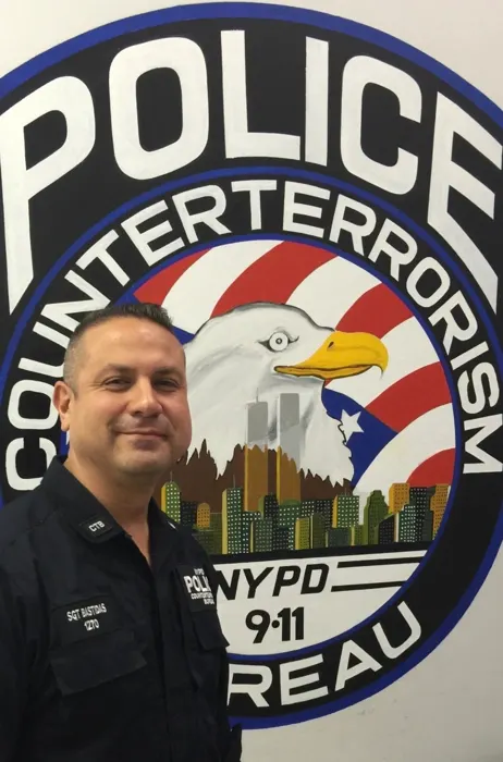 JC Bastidas in front of the NYPD Counterterrorism Bureau emblem